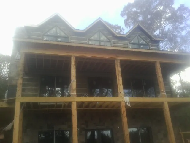 Dormers and porch framing on a large log home under construction — Roof Coating work by our crew in Crosby