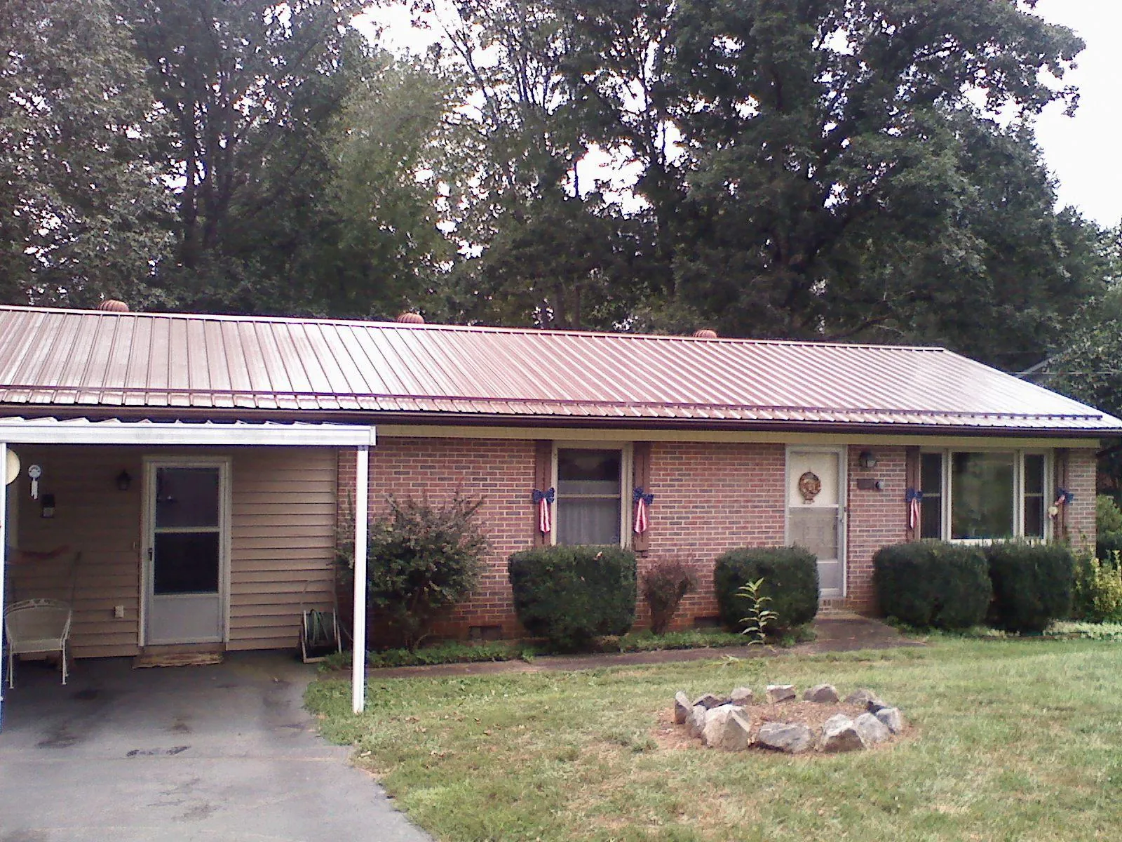 Bronze metal roof and carport on a brick ranch home — Roof Repair work by our crew in Crosby