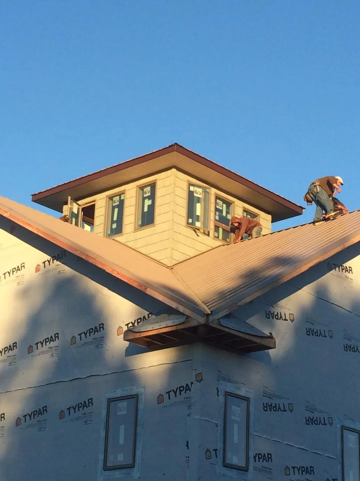 Roofers working around a rooftop cupola on a new metal roof at sunset — Roof Waterproofing in Crosby by Roofing Brothers